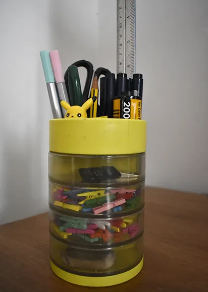 Portalápiz con marcadores, reglas y objetos creativos sobre escritorio de diseño