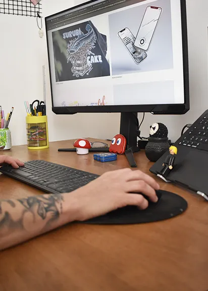 Mano trabajando con mouse frente a pantalla con proyectos de diseño web y branding